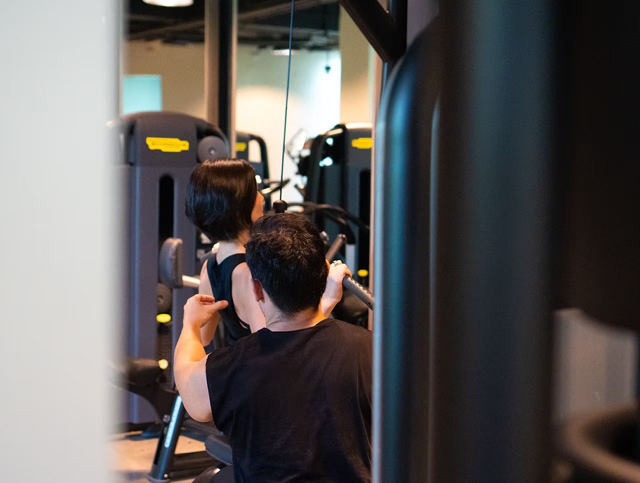 A coach guiding a member through a set on the selectorised machines of the Training Floor.