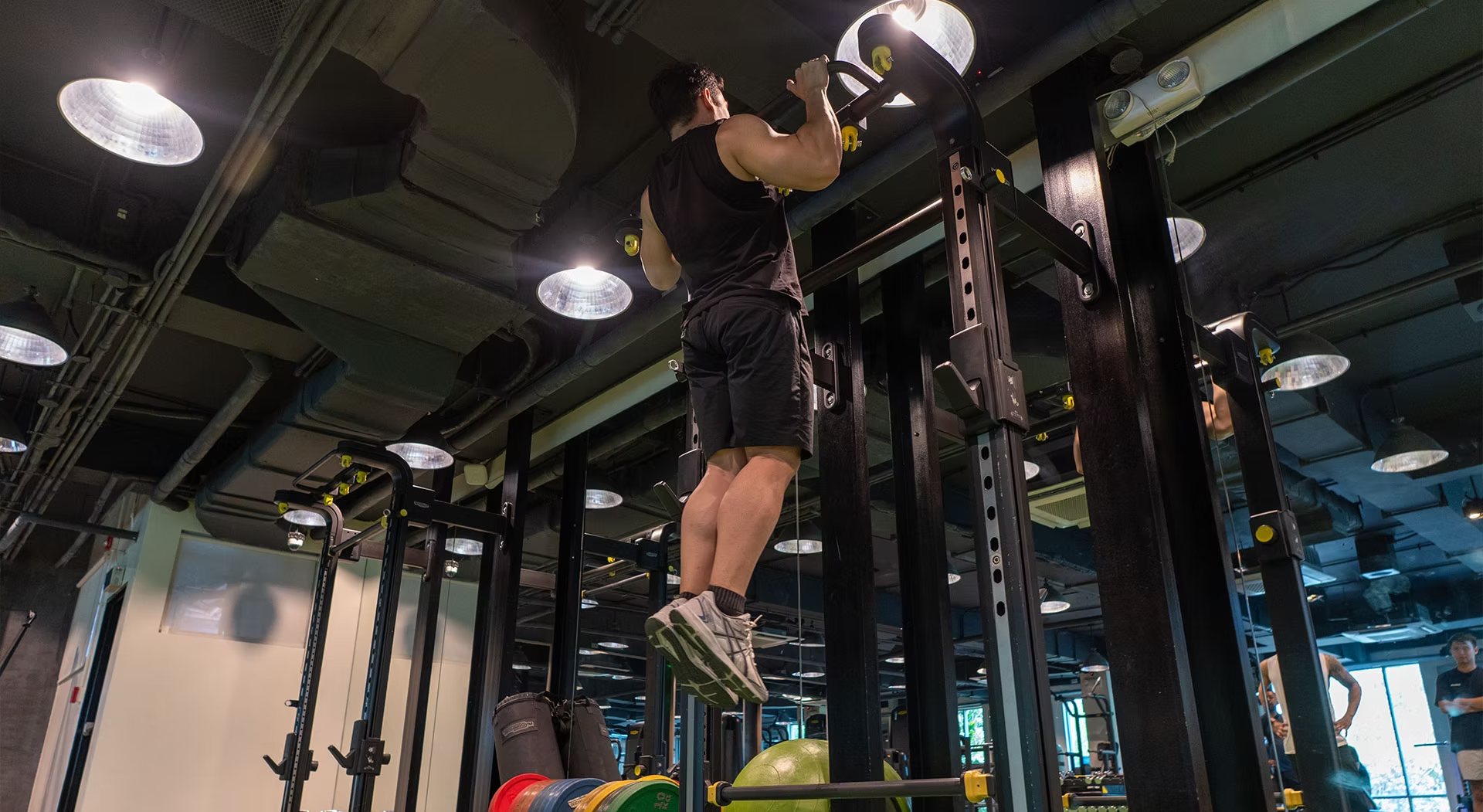 A member pulling up on the rack under the lights of the Atletica floor.