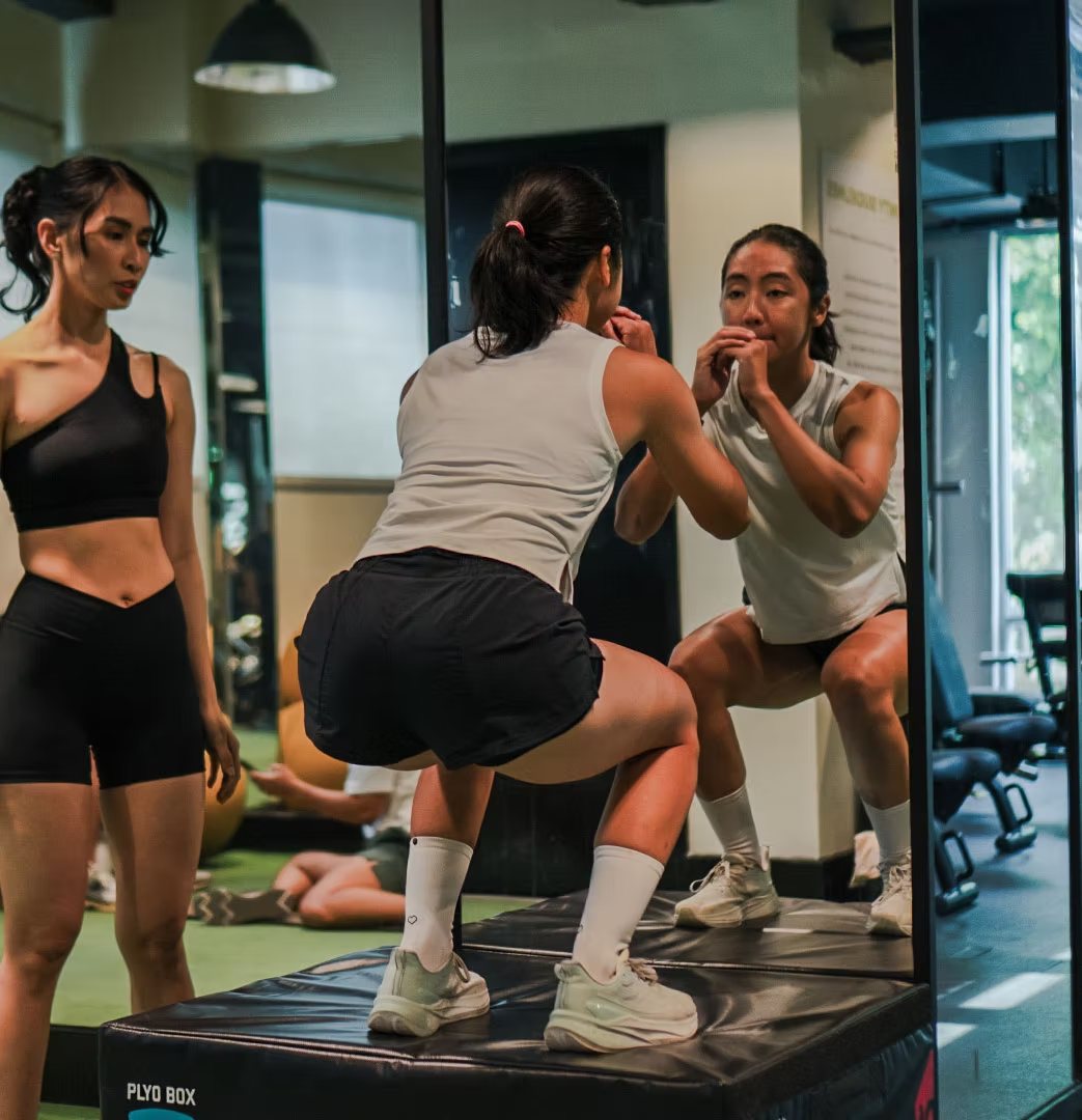 Members working through box jumps together in front of the mirror at Rockwell Atletica.