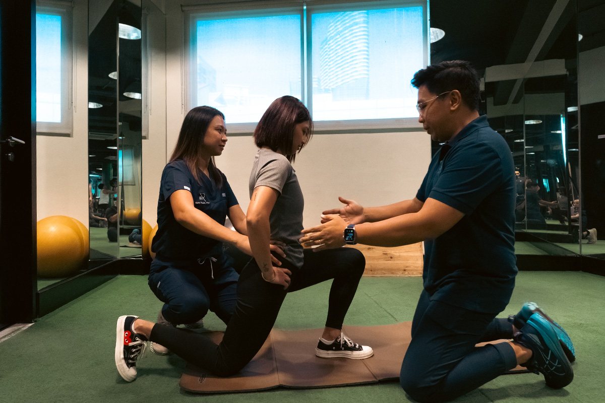 Two members of the recovery team assessing a member's lunge position on the floor.